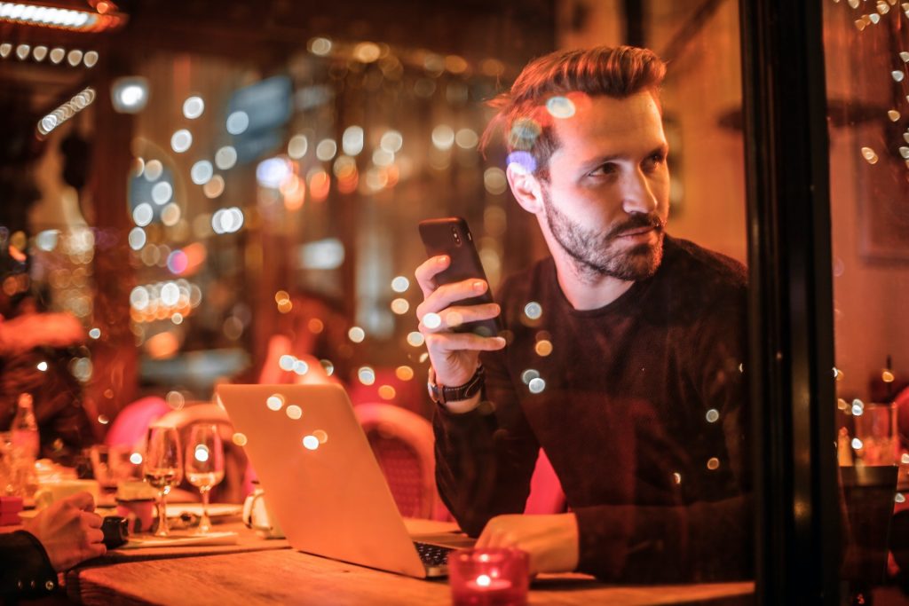 Mann sitzt im Restaurant mit Smartphone in der Hand Gästeregistrierung für Gastronomie Hotel und Handel